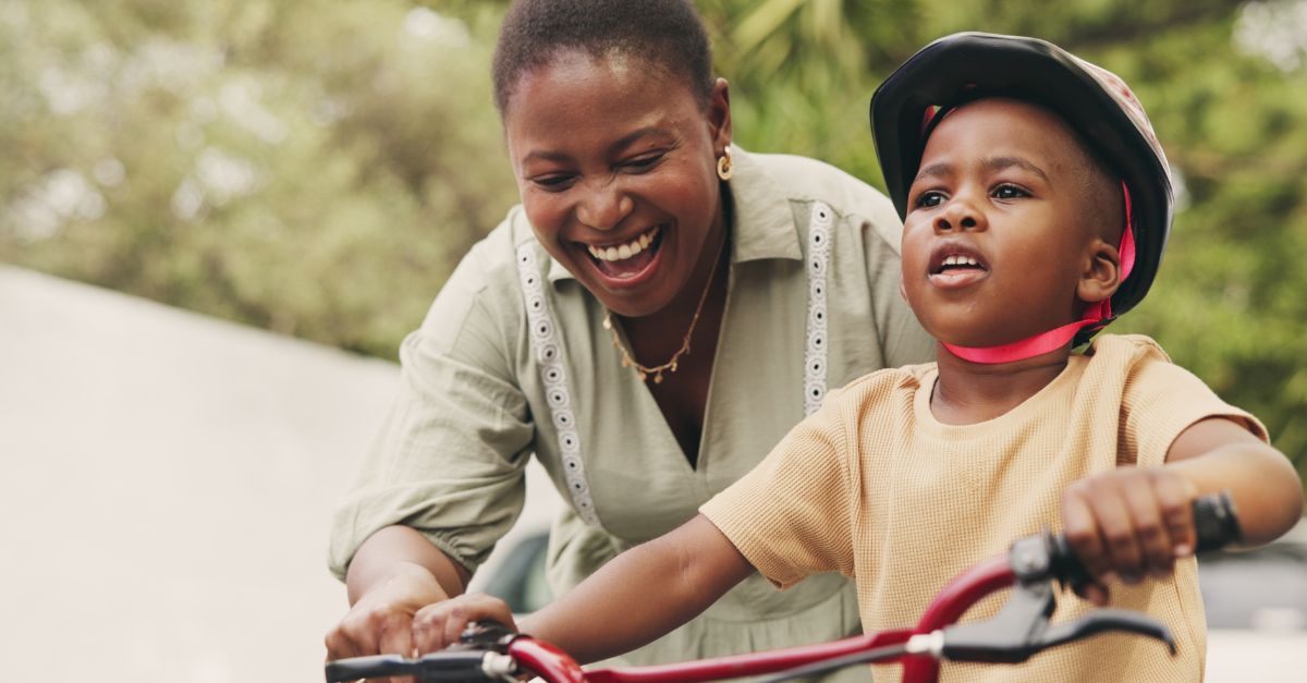 Slide-1 Black mother helping her son ride a bike